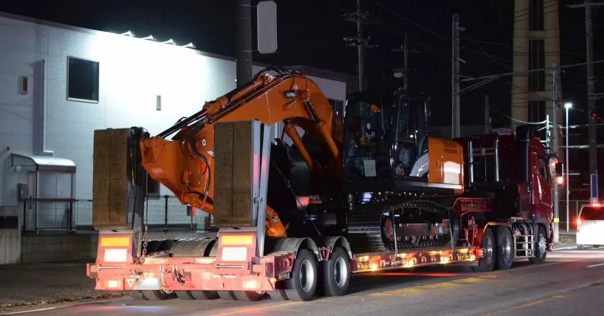 Lowboy trailer hauling a backhoe loader